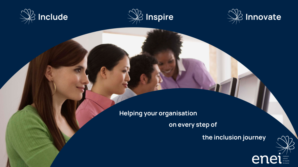 Group of ethnically diverse people sitting at a large desk with a person standing next to them, assisting them with a task.